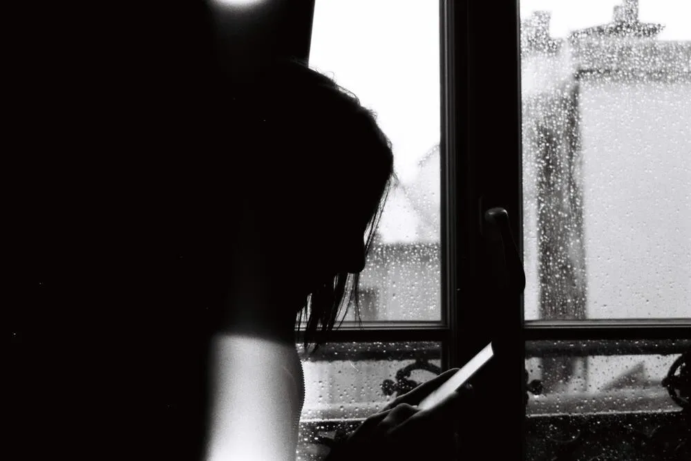 Silhouette looking through a rain-covered window